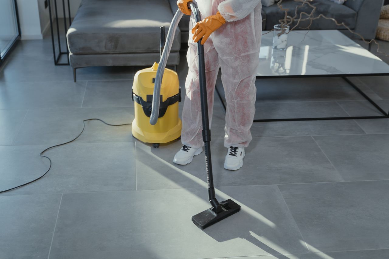 Crafting Captivating Headlines: Your awesome post title goes here A professional cleaner in protective gear vacuuming the floor in a modern living room.